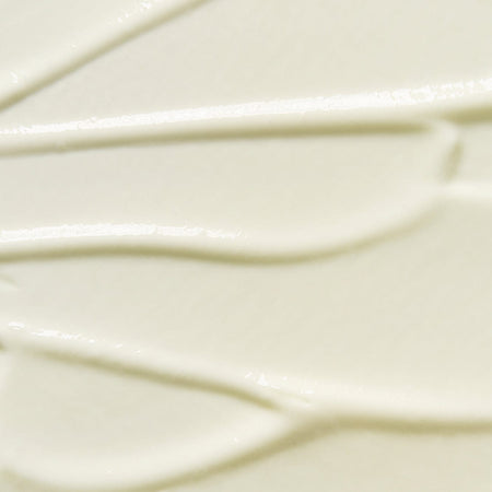 Close-up texture of Tropic Sun Day dewy facial SPF 50 sunscreen, showing smooth creamy consistency with subtle swirls.
